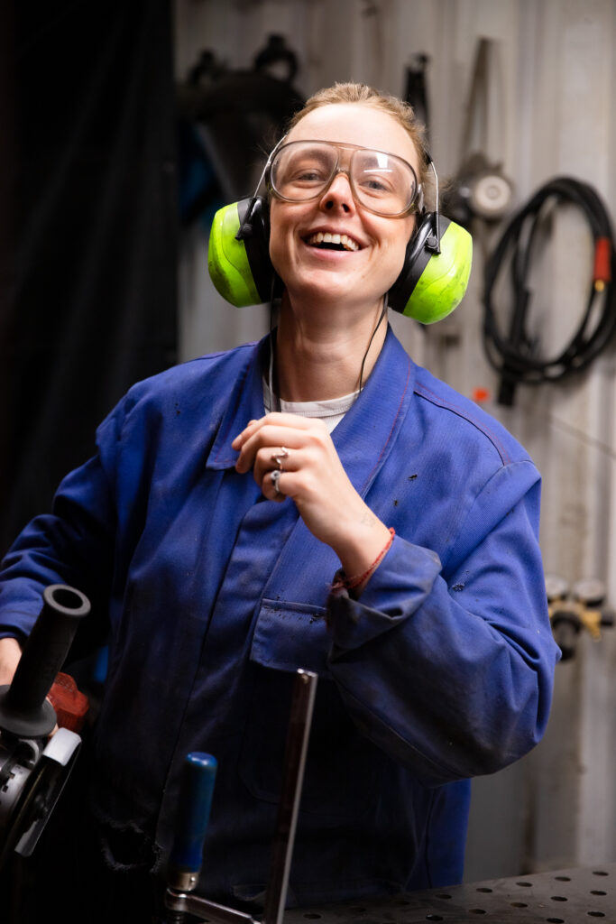 Creatorin in ihrer Werkstatt beim arbeiten und mit Schutzbrille, Blaumann und Gehörschutz
